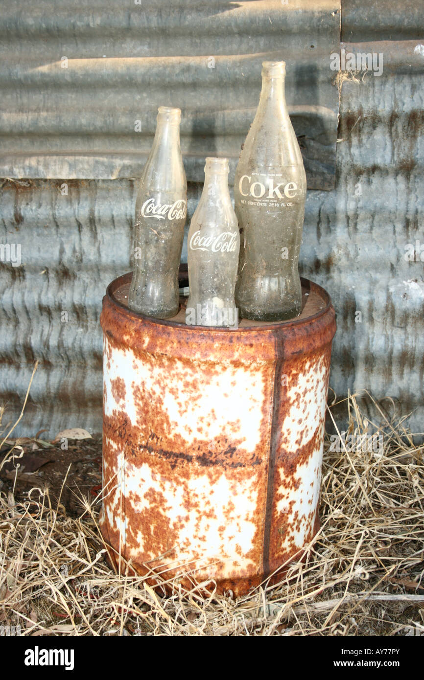 Tre vecchie bottiglie di Coca Cola in piedi su un vecchio combustibile può Foto Stock