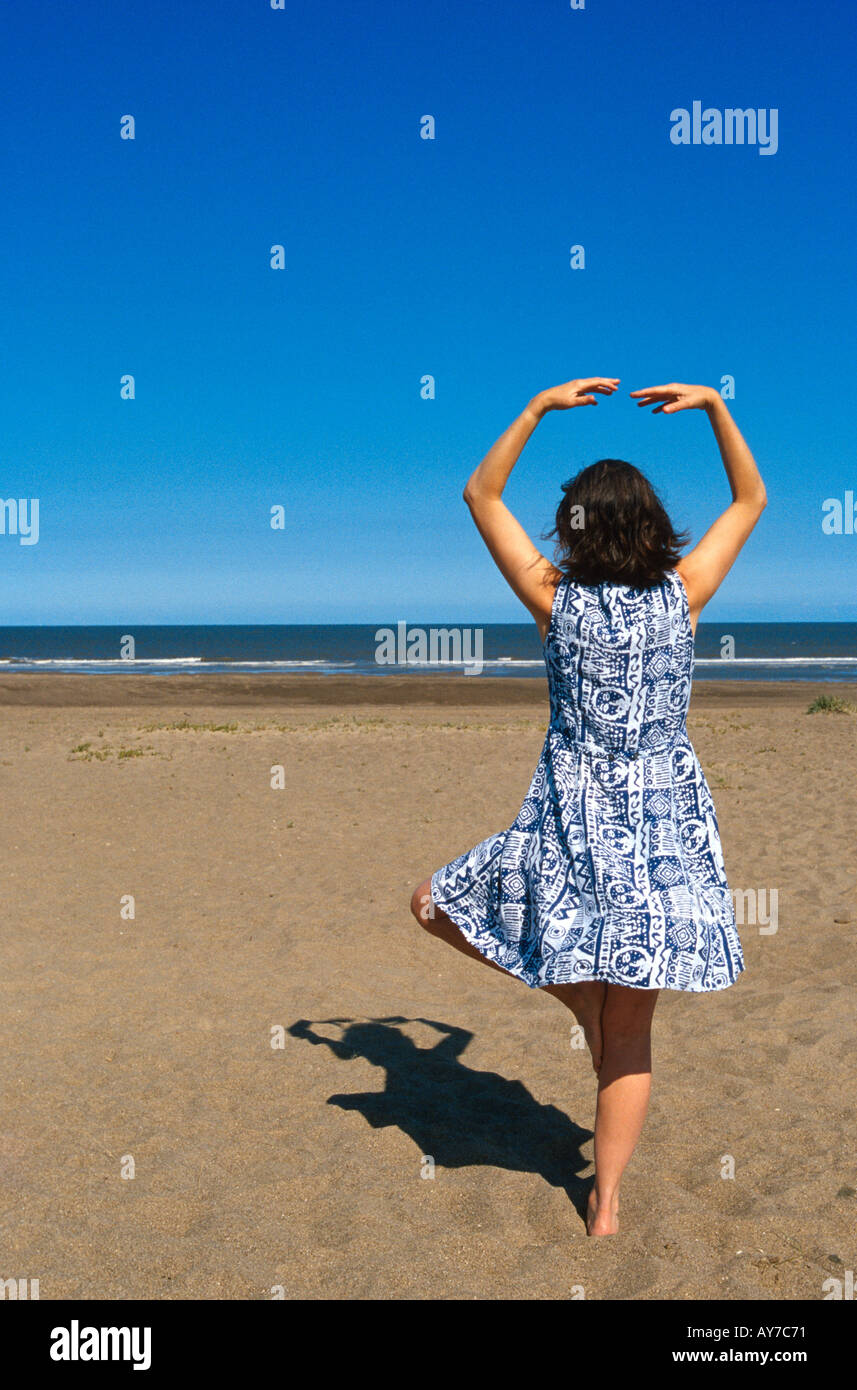 Giovane donna su una spiaggia a praticare yoga Foto Stock
