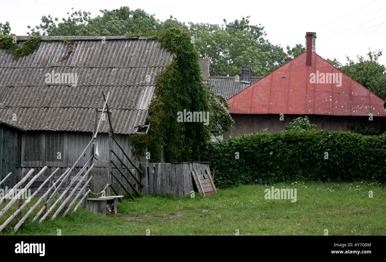 Rural farm house, legnaia e edificio rosso con tetto di tegole, vecchio recinto in legno erba Foto Stock