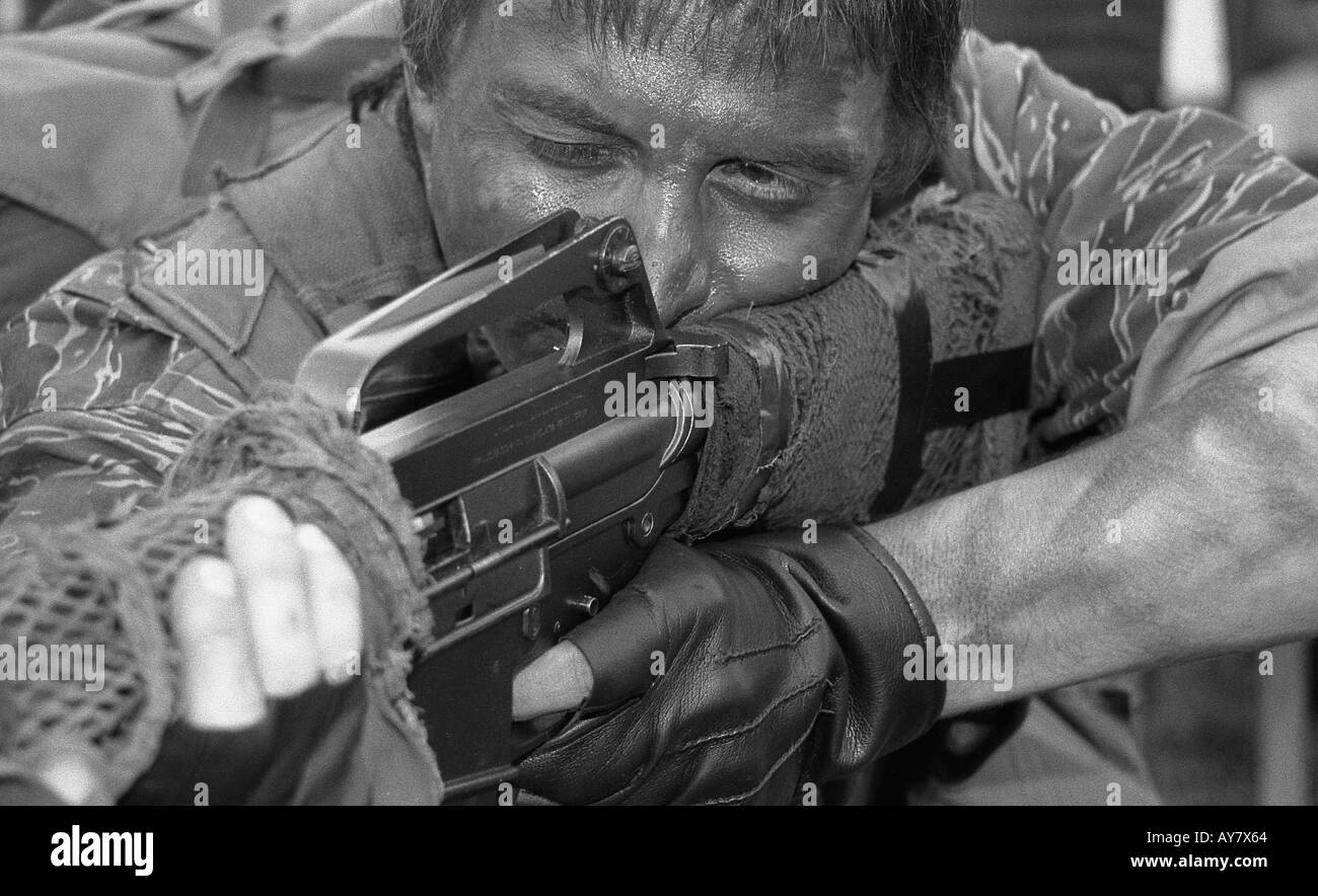 Uomo dalla società militare con M16 fucile in posizione di sparo e indossando Guerra del Vietnam Forze Speciali americane di vestiti. Foto Stock