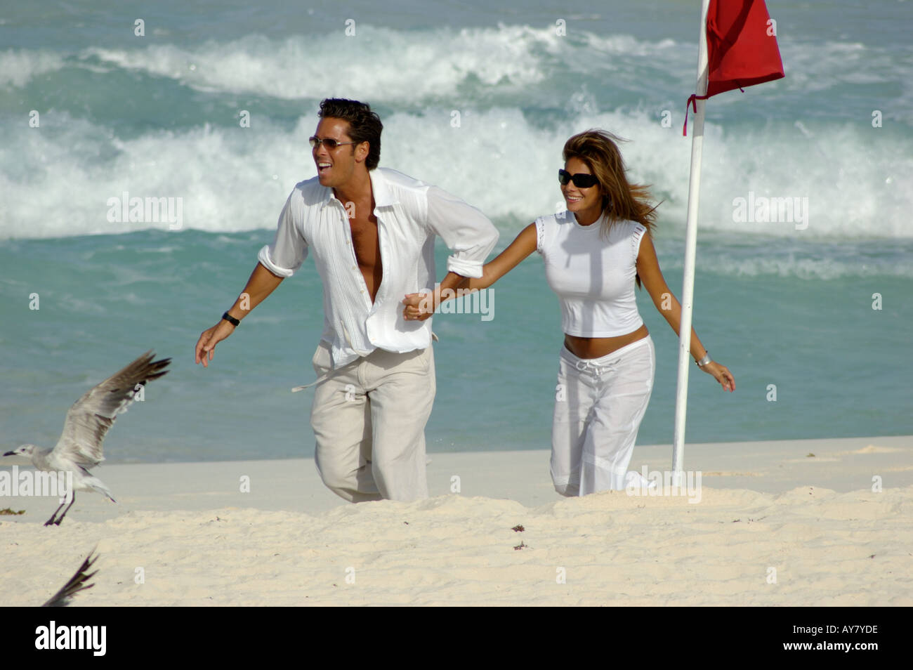 Coppia attraente prendendo una romantica passeggiata sulla spiaggia tenendo le mani Foto Stock