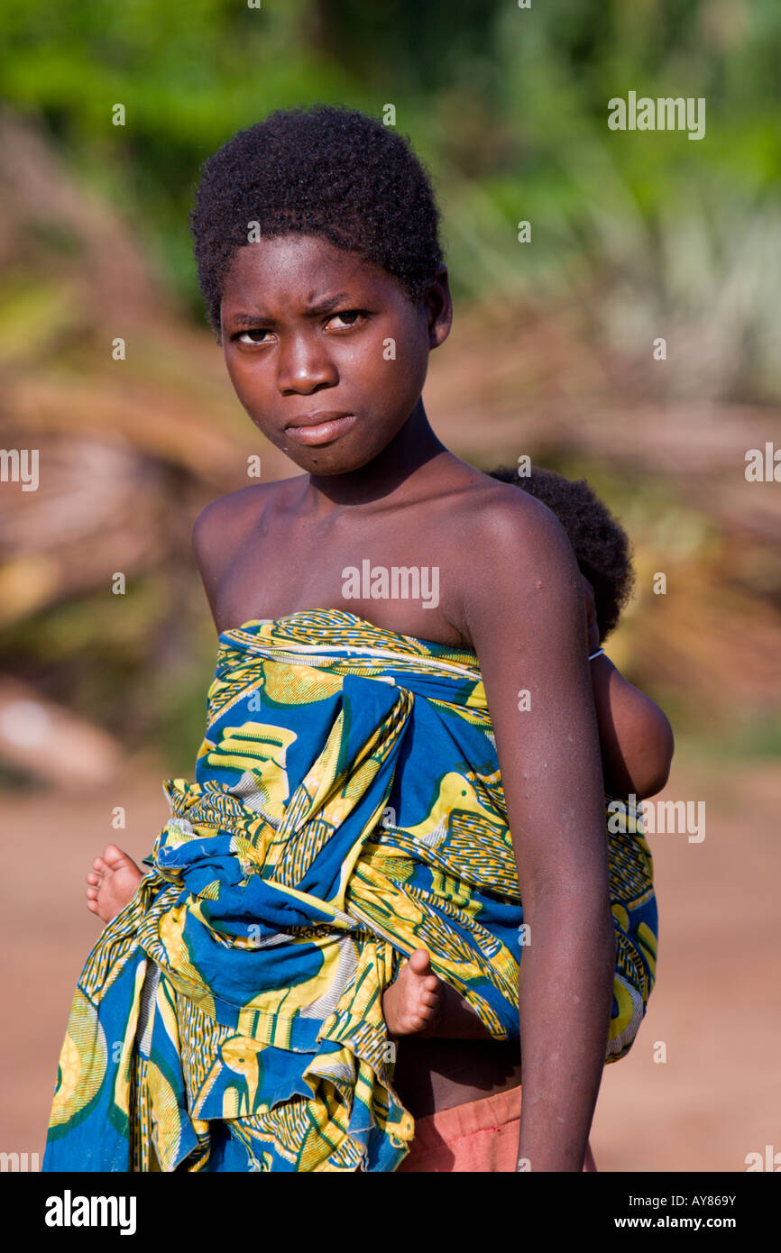 Una giovane ragazza africana porta un bambino sulla schiena avvolto in un tradizionale pagne Foto Stock