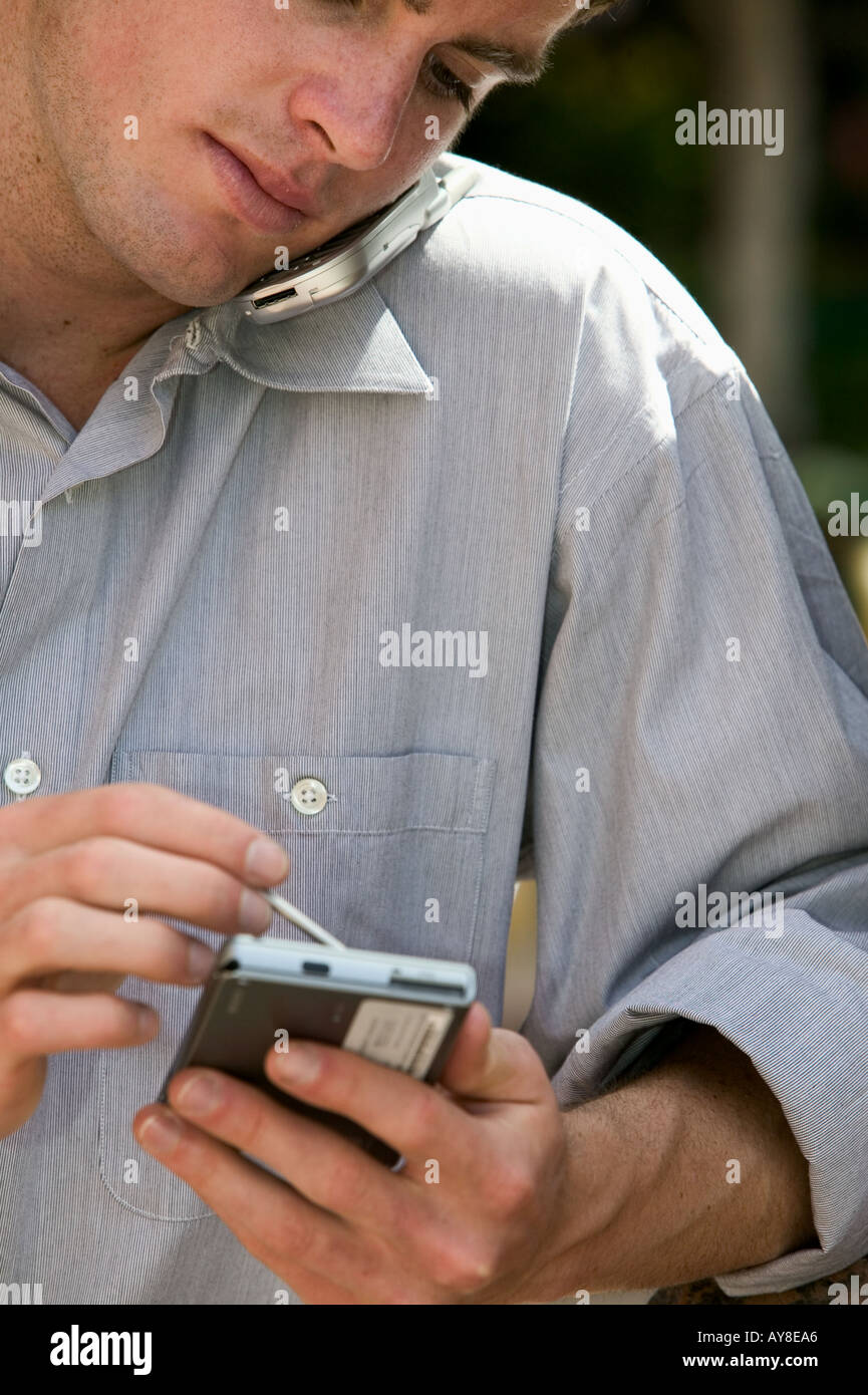 Business man parlando al telefono cellulare e di utilizzo di PDA Foto Stock