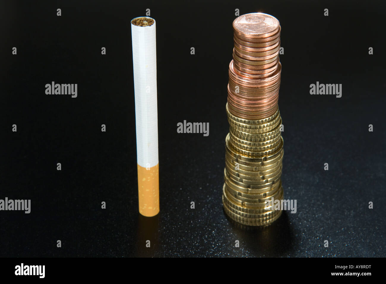 Sigaretta accanto alla pila di monete, close-up Foto Stock