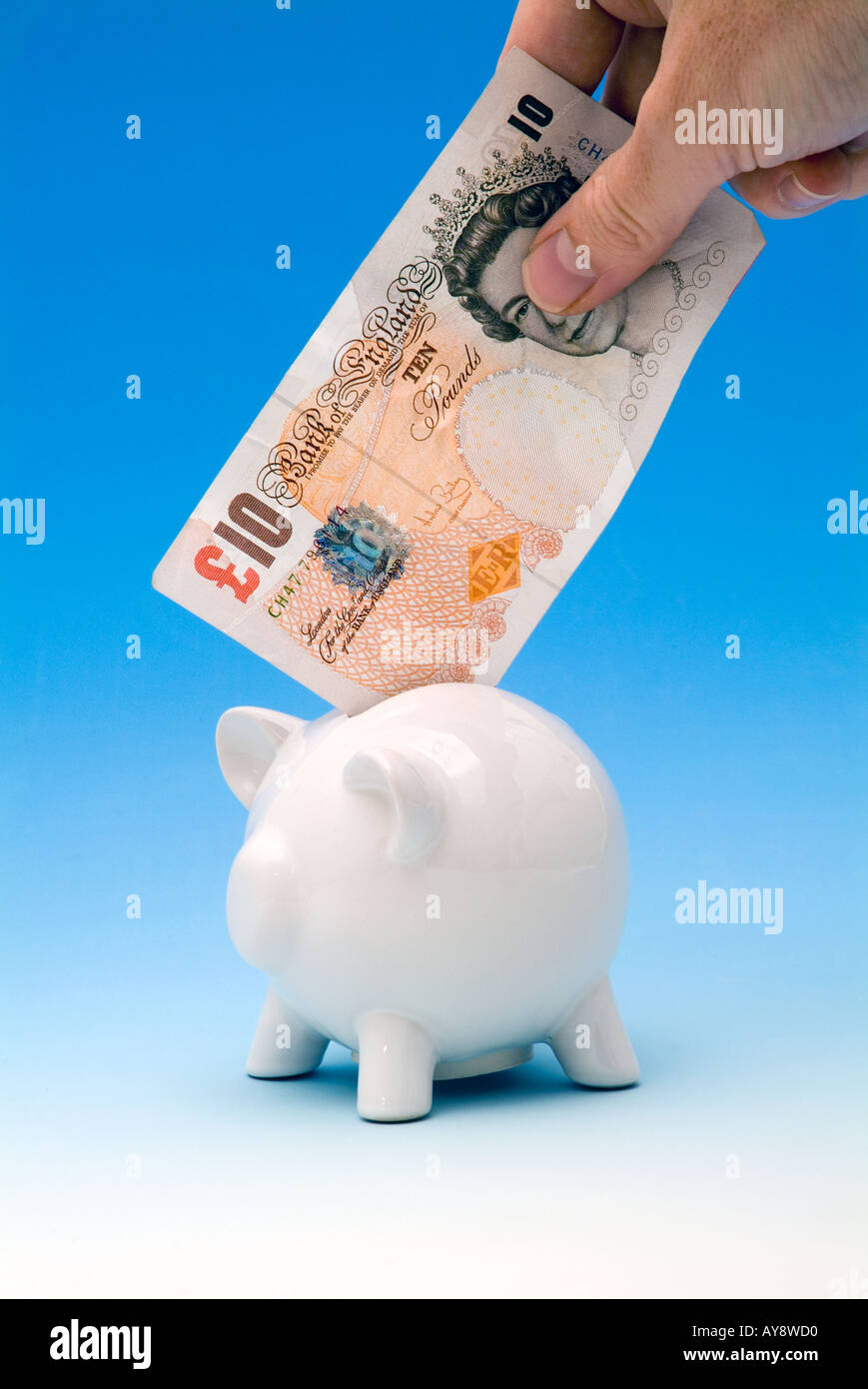 Mettendo mano dieci libbre in un piggy-bank Foto Stock