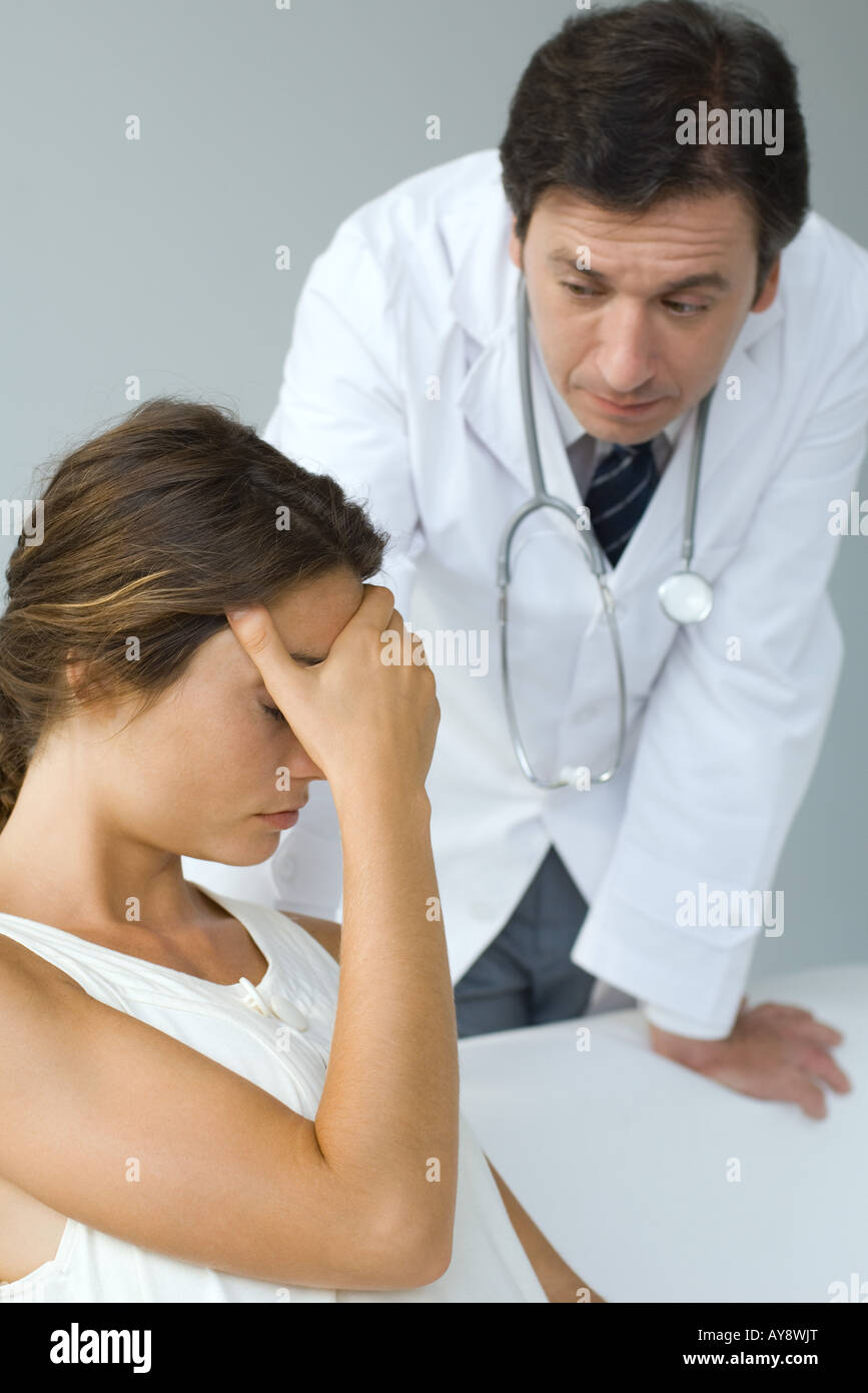 Maschio esame medico paziente, donna seduta con la mano sopra gli occhi Foto Stock