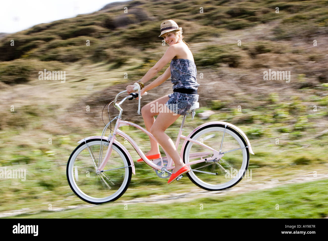 Ragazza in bici in abito senza spalline e cappello Foto Stock