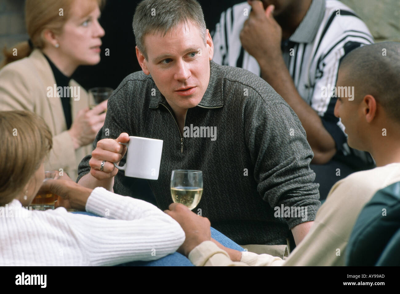 Bianco uomo caucasico di bere il caffè mentre gli amici amano il vino al cocktail party Foto Stock