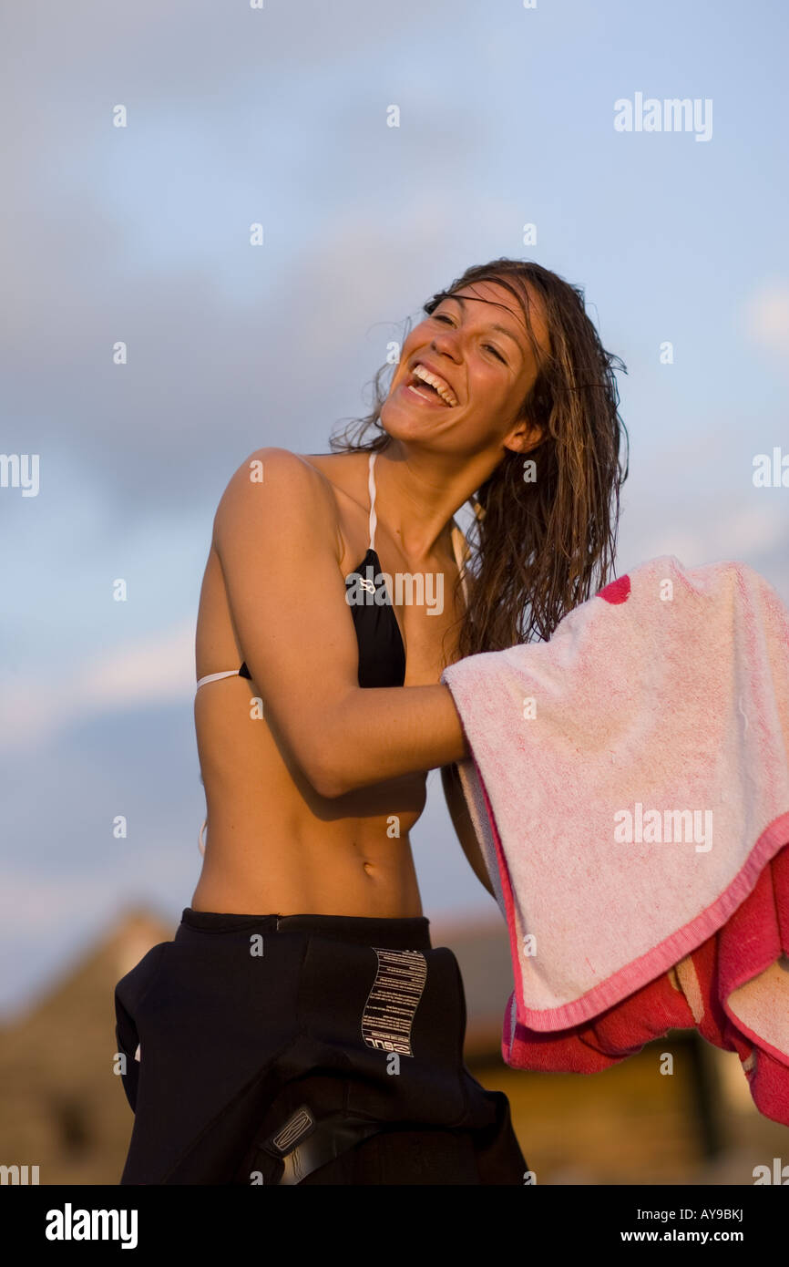 Surfista femmina asciugando i capelli con un asciugamano, Cornwall, Regno Unito Foto Stock