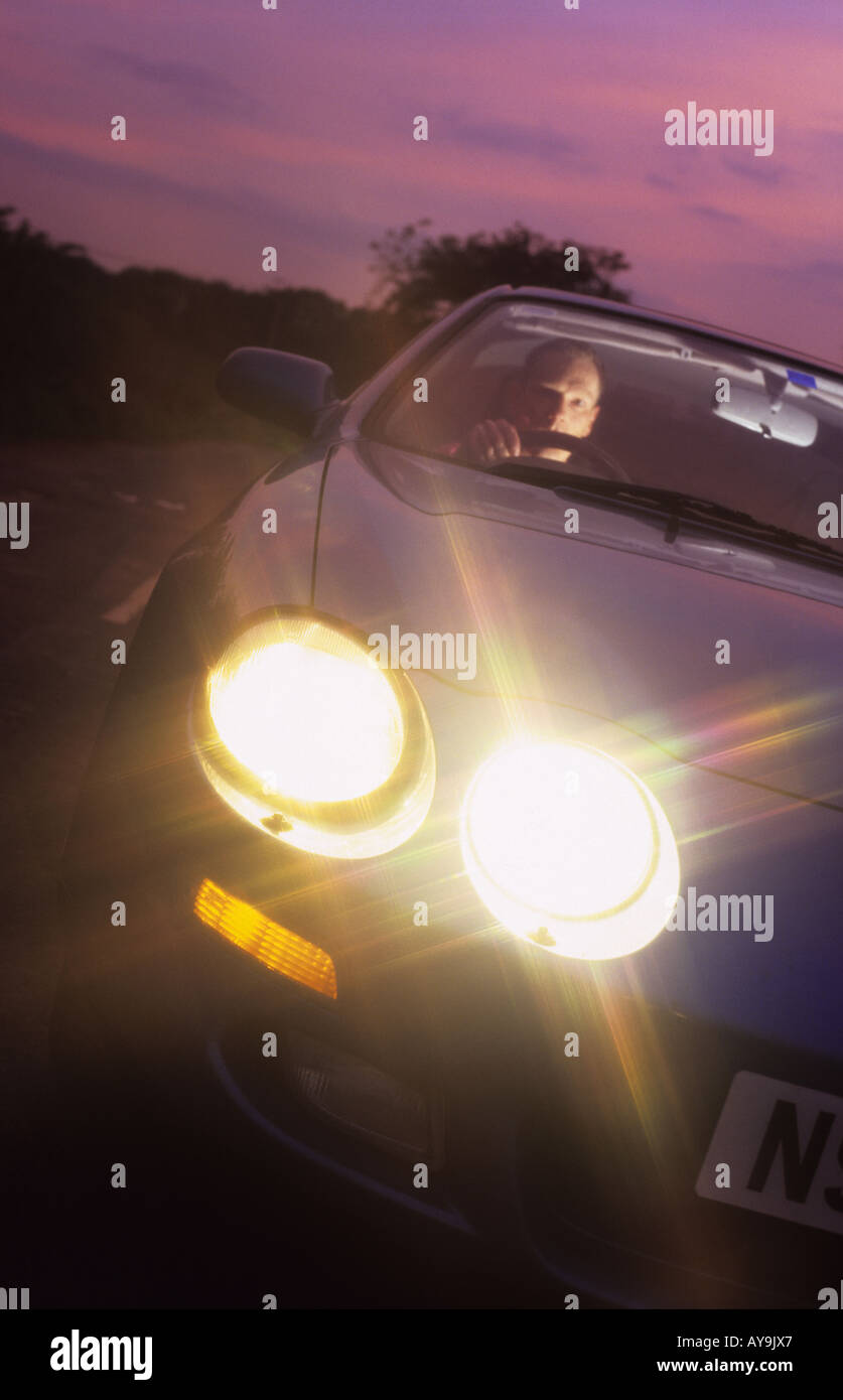 Uomo alla guida di Auto down vicolo del paese al tramonto leeds Yorkshire Regno Unito Foto Stock