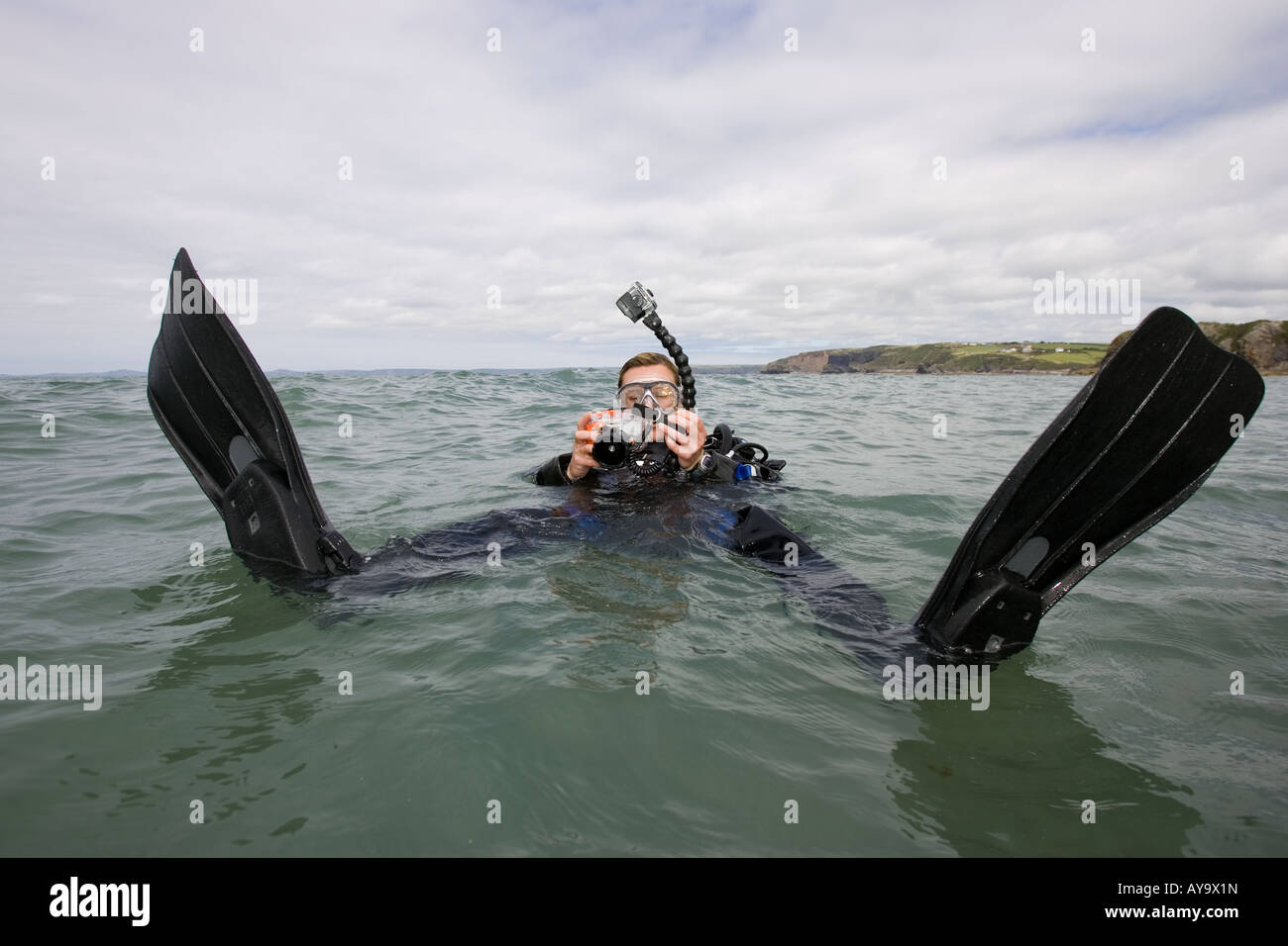 Scuba Diver regolazione della fotocamera mentre galleggiante sull'acqua Foto Stock