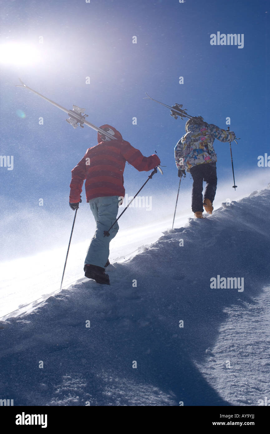 Due gli sciatori trasportare equipaggiamenti fino ripido pendio di montagna, Tignes, Francia Foto Stock