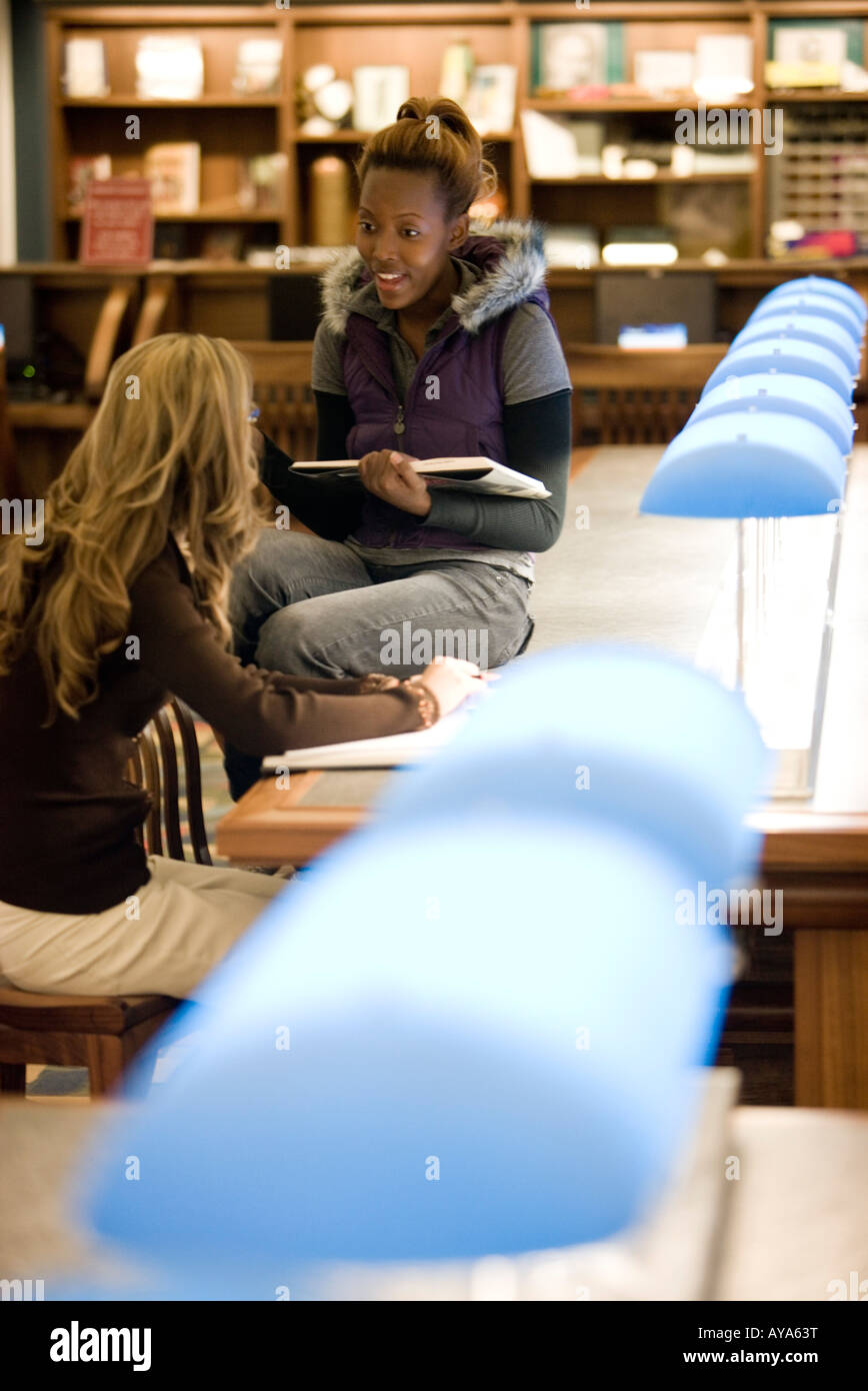 Due giovani donne seduti nella sala di lettura della biblioteca Foto Stock