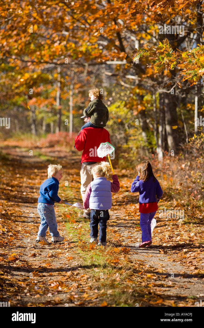Un uomo porta il suo figlio(4 anni) sulle sue spalle su un sentiero di bosco in Biddeford, Maine. Tre bambini seguire. Foto Stock