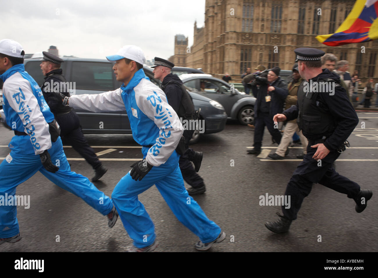 Cinese non identificato la sicurezza eseguire con la Metropolitan Police e la torcia olimpica durante la London Tibet proteste in piazza del Parlamento Foto Stock