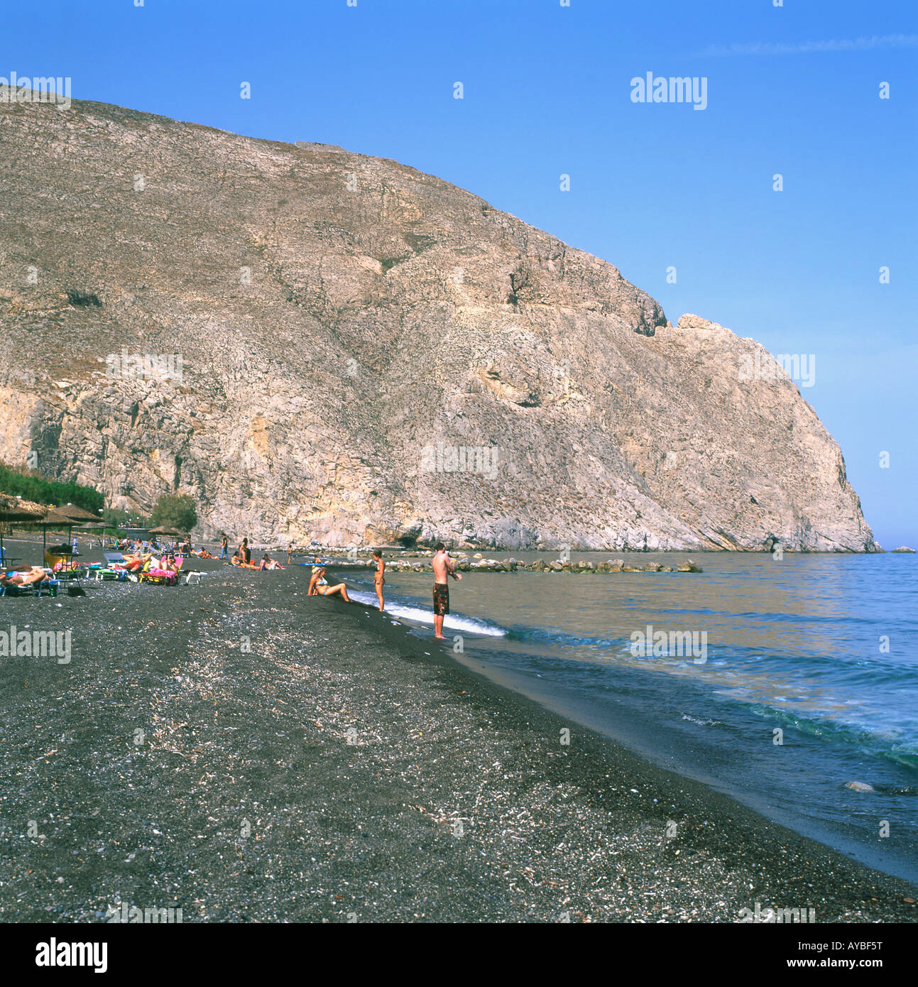 Le persone in vacanza a prendere il sole in mare sul nero spiaggia vulcanica a Perissa Santorini isole greche in grecia Europa KATHY DEWITT Foto Stock
