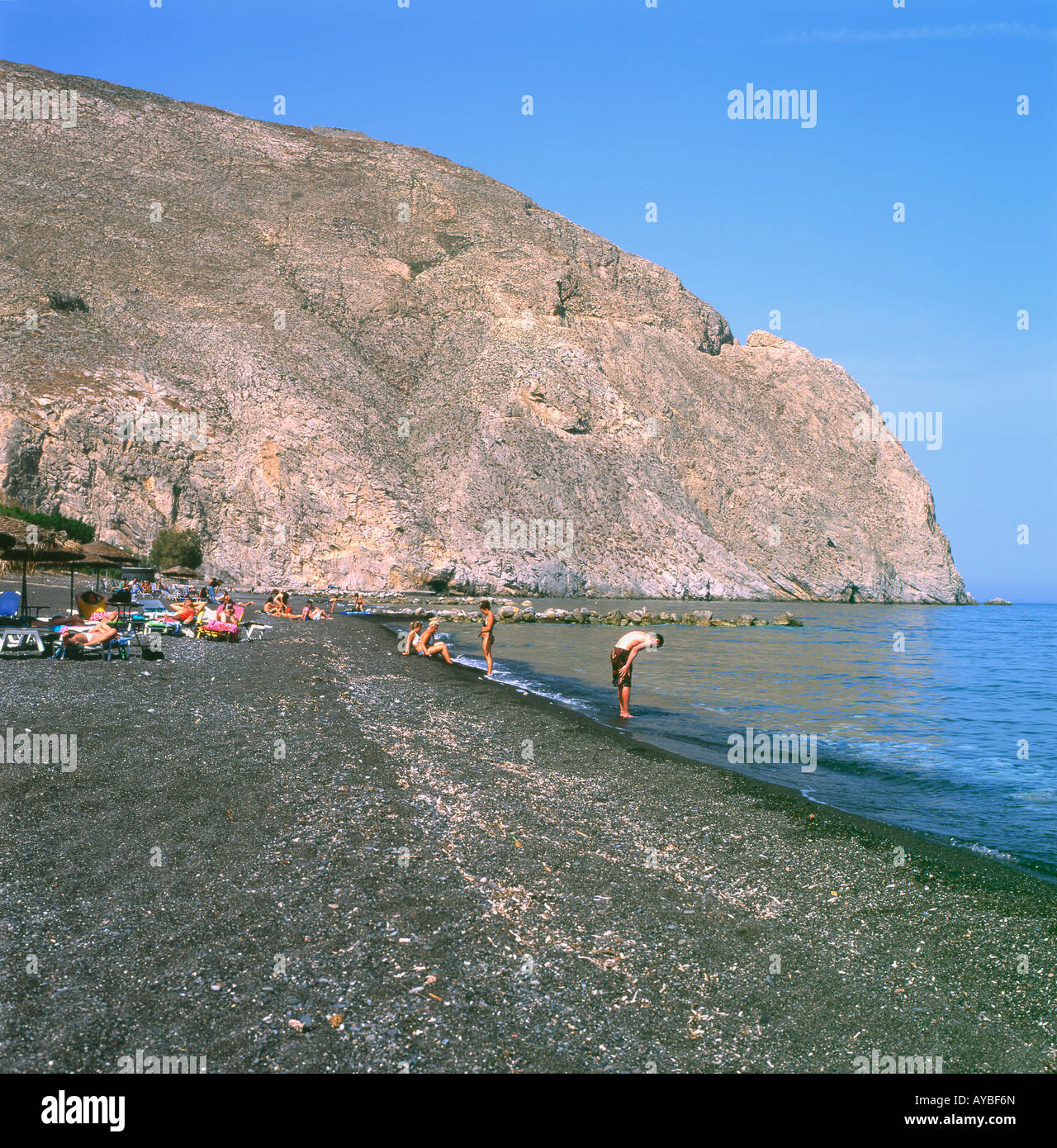 Persone sole rilassante in riva al mare sul nero spiaggia vulcanica a Perissa Santorini Isole Greche 2007 KATHY DEWITT Foto Stock