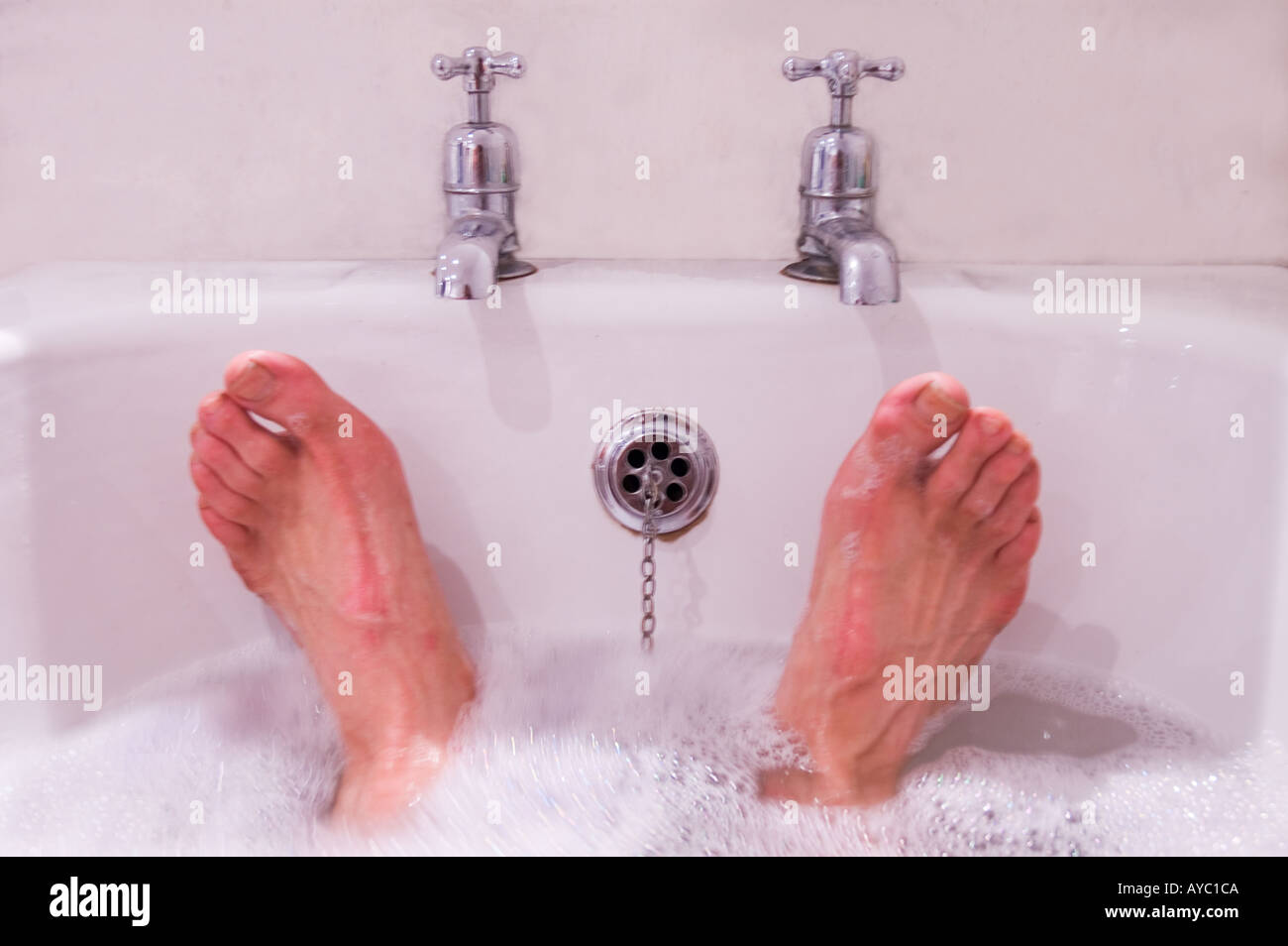 Una vista di un mans piedi e rubinetti del bagno. Foto Stock