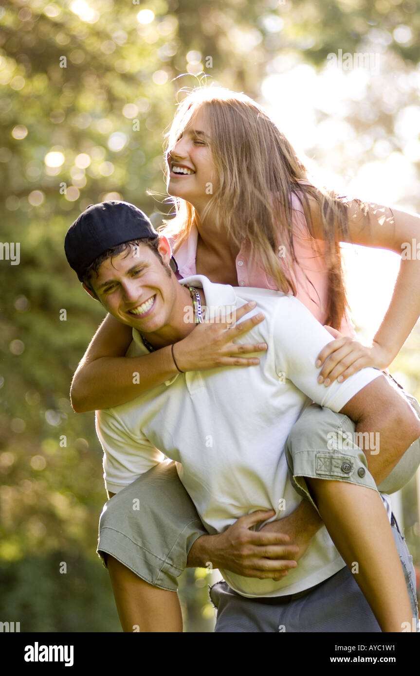 Giocoso ragazzo adolescente che porta a ridere ragazza adolescente sulle sue spalle. Foto Stock