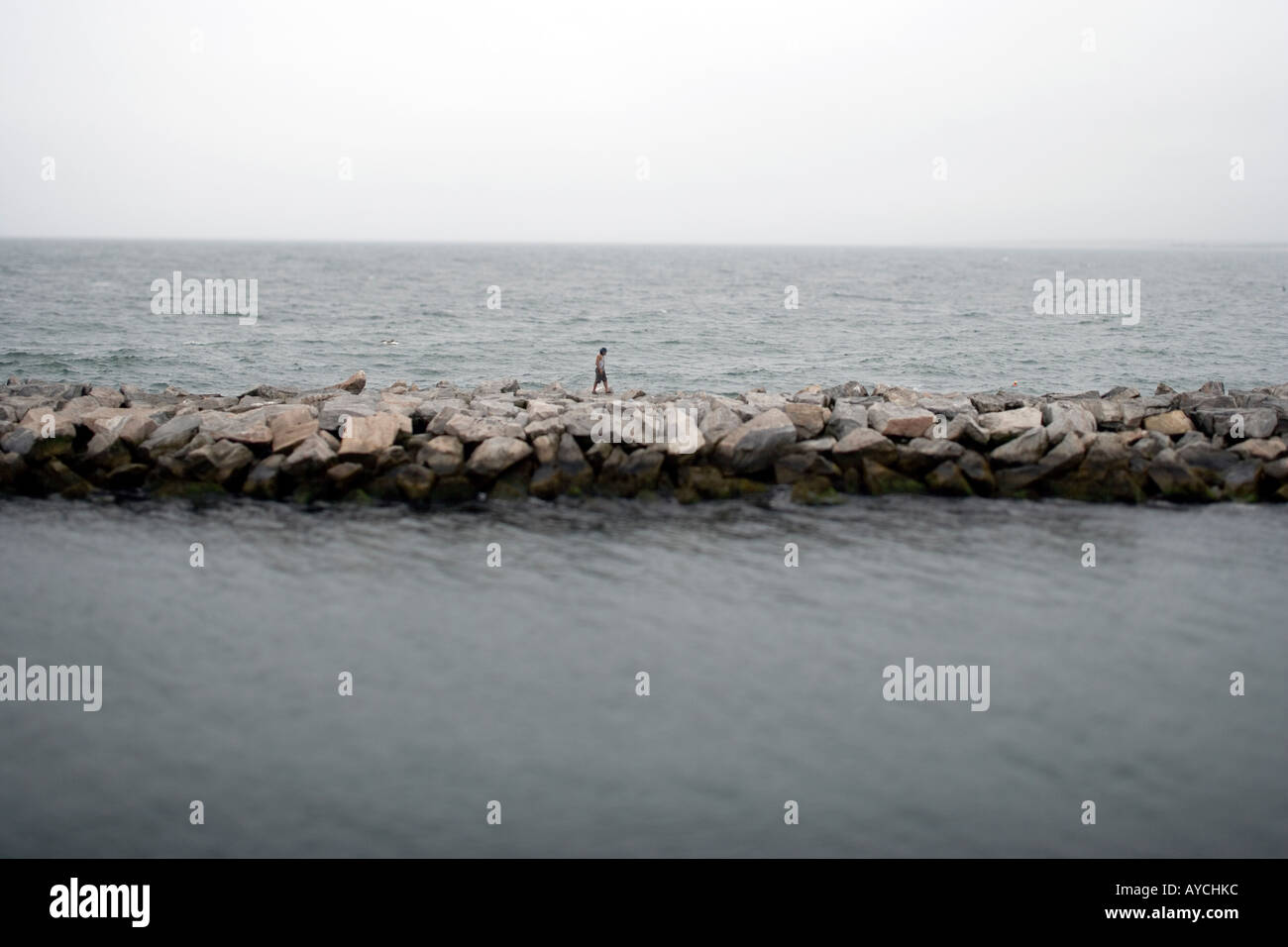 Una solitaria figura passeggiate lungo un molo da soli Foto Stock