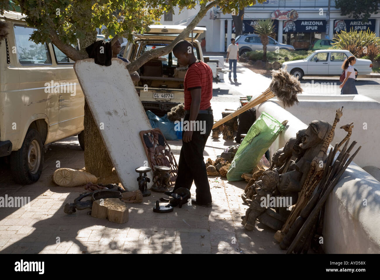 Uomo in piedi con sculture scolpite e altri oggetti in vendita, nel mercato africano fuggire a Stellenbosch, Capo Occidentale, Sud Africa Foto Stock