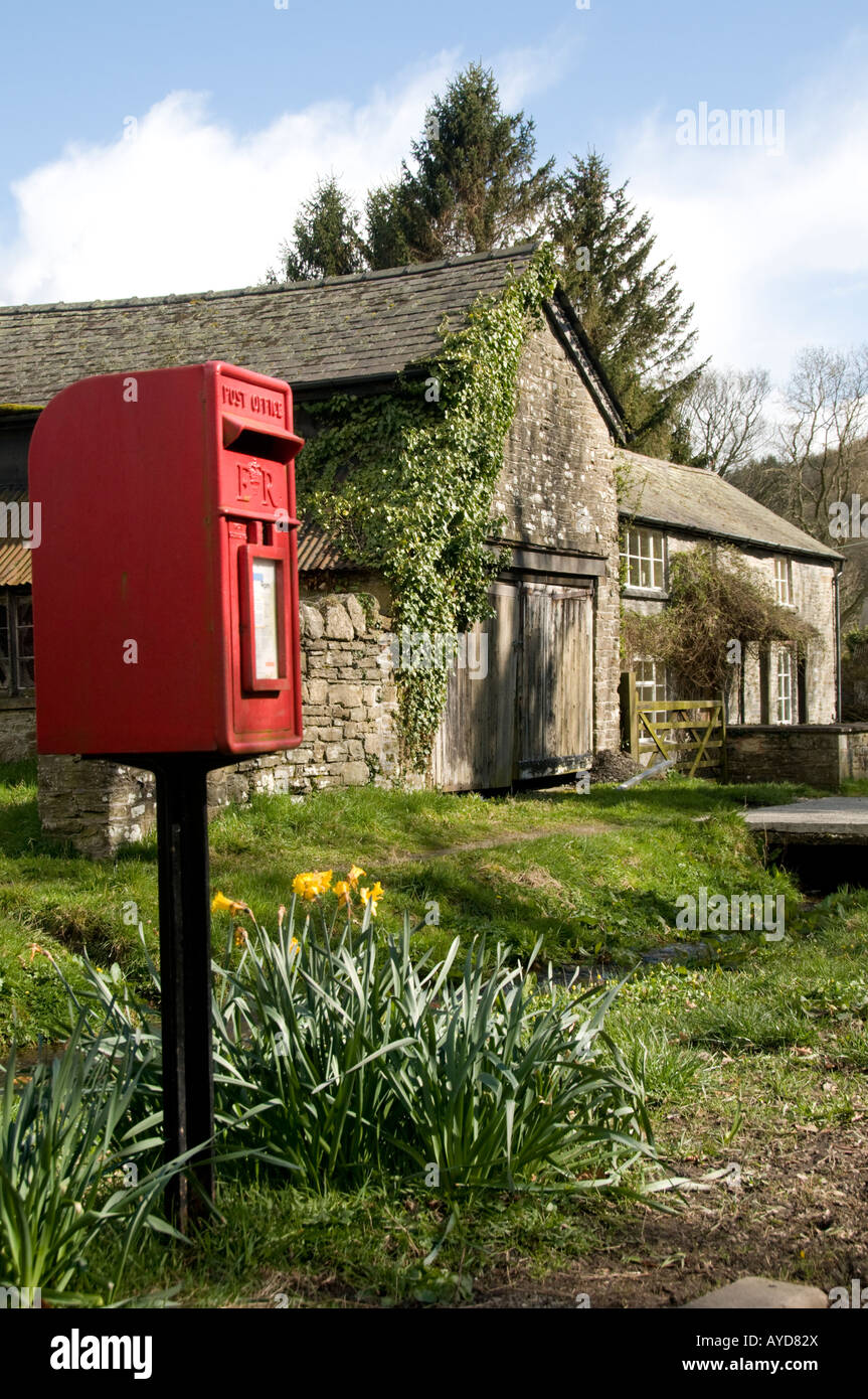 Letterbox rosso e la vecchia casa in acqua Street New Radnor village Powys Galles centrale un flusso corre giù road di fronte agli edifici Foto Stock