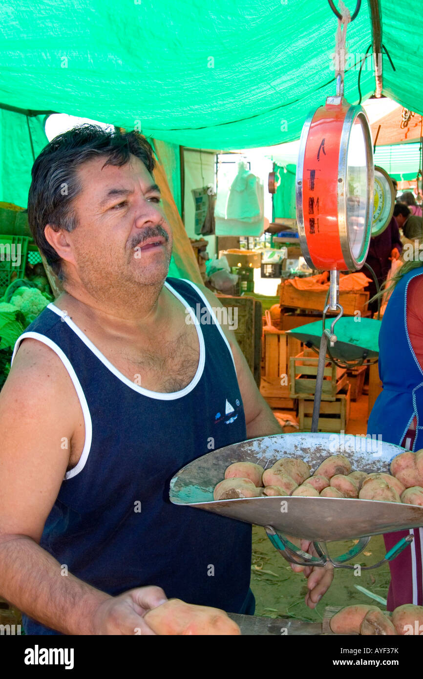 Uomo del peso di patate su una bilancia a molla in un esterno di produrre mercato in Valparaiso Cile Foto Stock