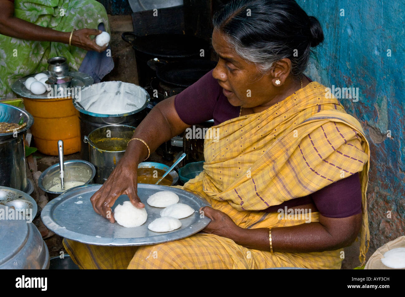 Donna che serve Idlies ad un cibo all'aperto in stallo a Madurai India del Sud Foto Stock