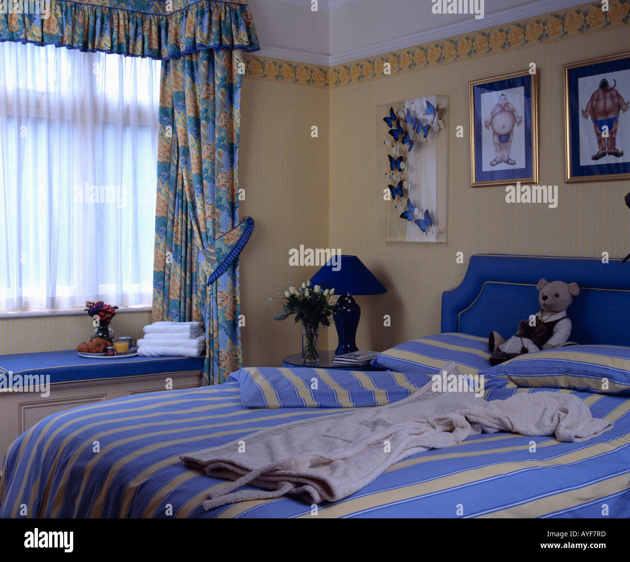 Tende blu e a strisce blu biancheria da letto in camera da letto giallo  Foto stock - Alamy