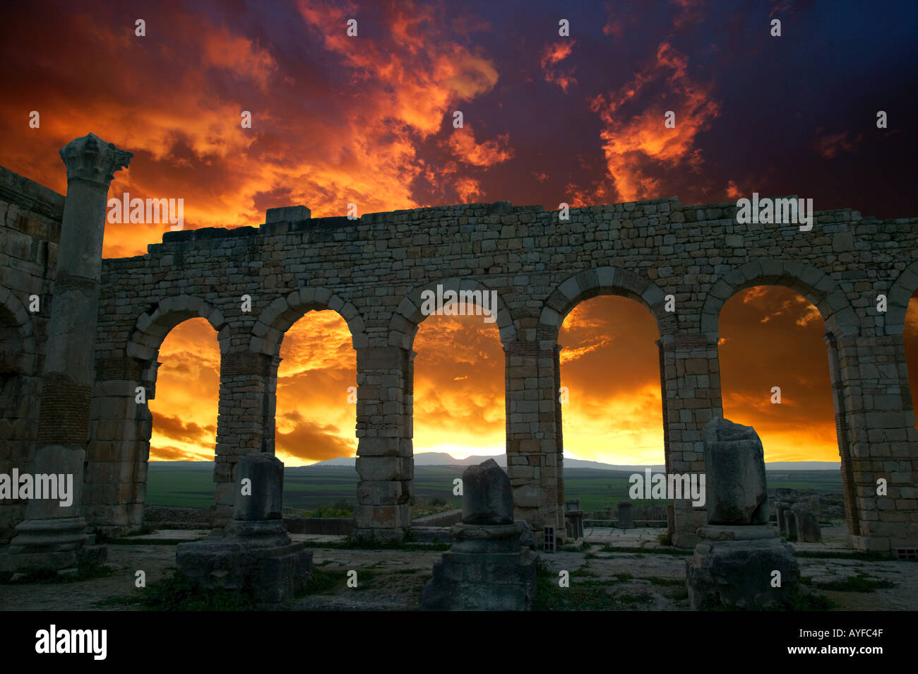 Volubilis rovine Romane risale al 2 ° e 3 ° secolo D.C. Tramonto contorni curvi di arcate della Basilica del Marocco Foto Stock