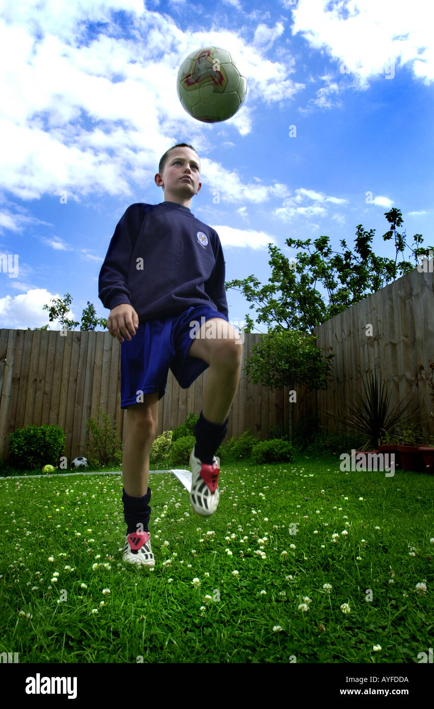 Ragazzo gioca con un calcio nel suo giardino sul retro Foto Stock
