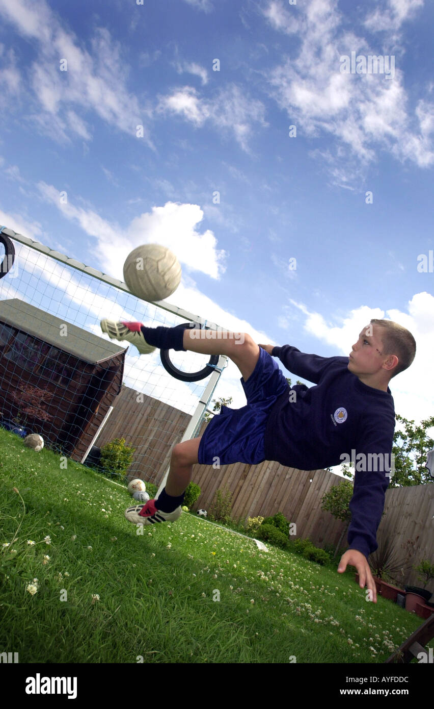 Ragazzo gioca con un calcio nel suo giardino sul retro Foto Stock