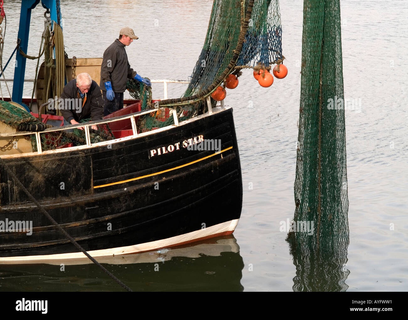 Pulizia dei pescatori reti sulla storica Pilota di Barca stella a Maryport harbour Cumbria Regno Unito Foto Stock