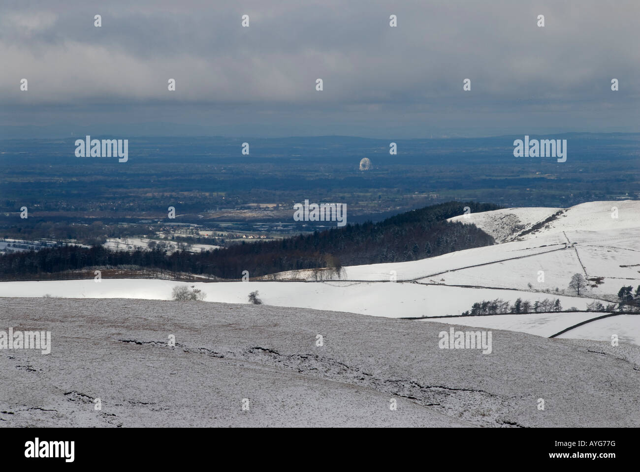 Vista su tutta la pianura del Cheshire dal Cat Fiddle con Jodrell Bank illuminata dal sole nel centro di neve in primo piano Foto Stock