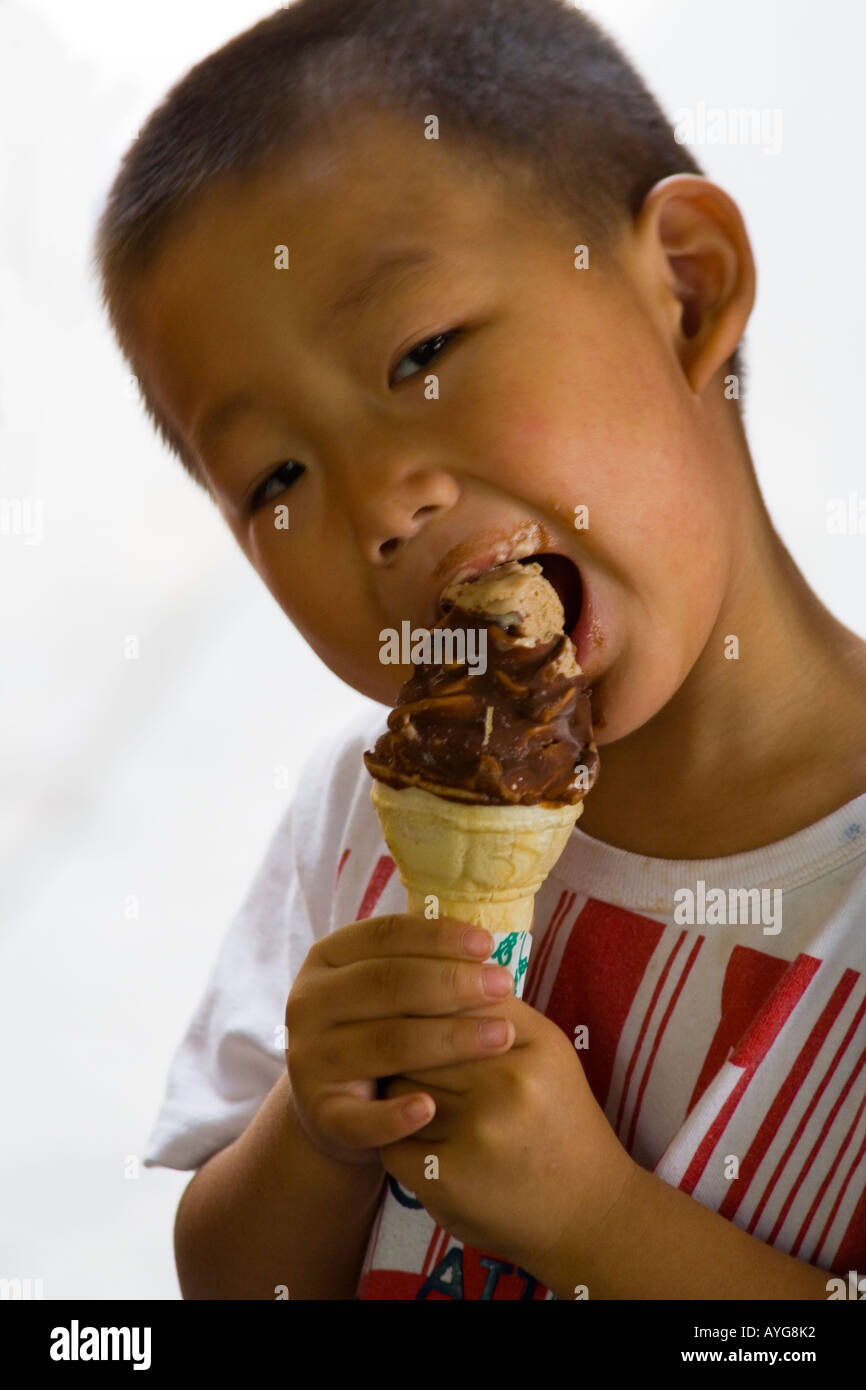 Giovani cinesi bambino mangia un cioccolato immerso cioccolato Crema ghiacciata di cono, Pechino, Cina Foto Stock