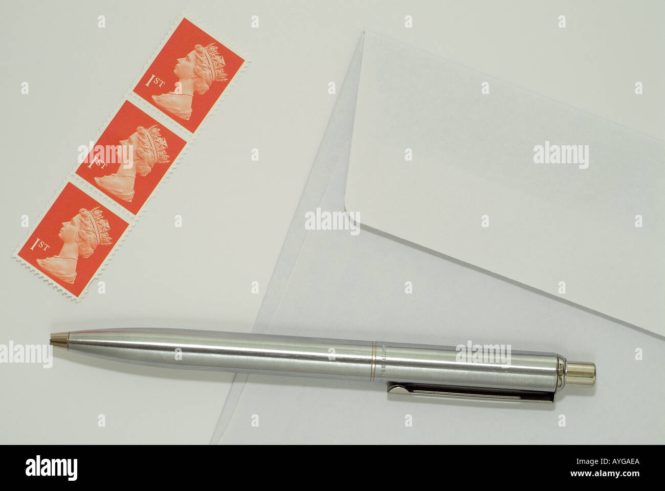 Regno Unito prima classe i francobolli e la penna su carta da scrivere accanto alle buste. Foto Stock
