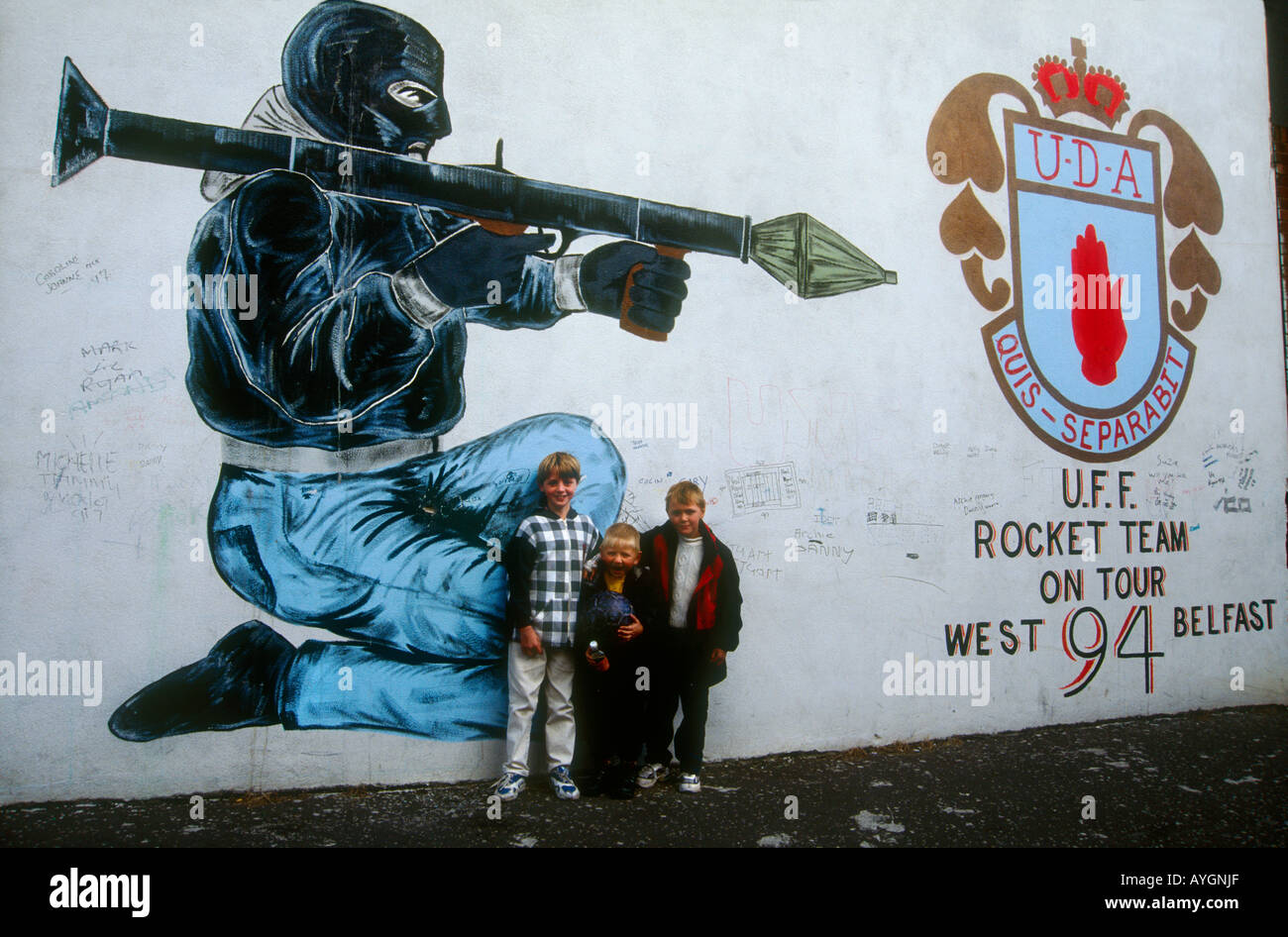 Bambini che giocano tra i lealisti murale di combattenti paramilitari, West Belfast Foto Stock