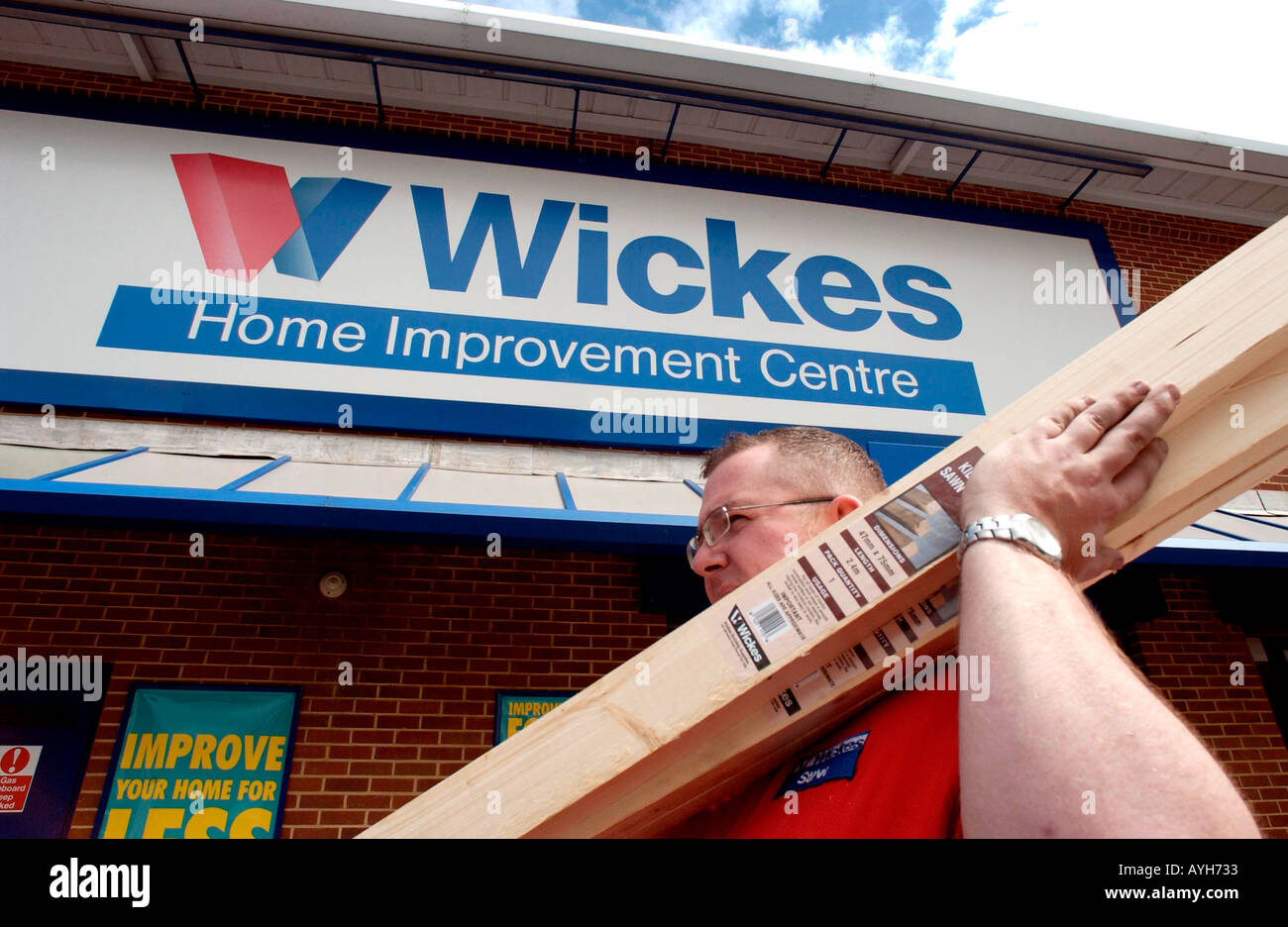 Un maschio tubby assistente presso un Wickes negozio DIY porta tavole di legno Foto Stock Un maschio tubby assistente presso un Wickes negozio DIY porta tavole di legno Foto Stock