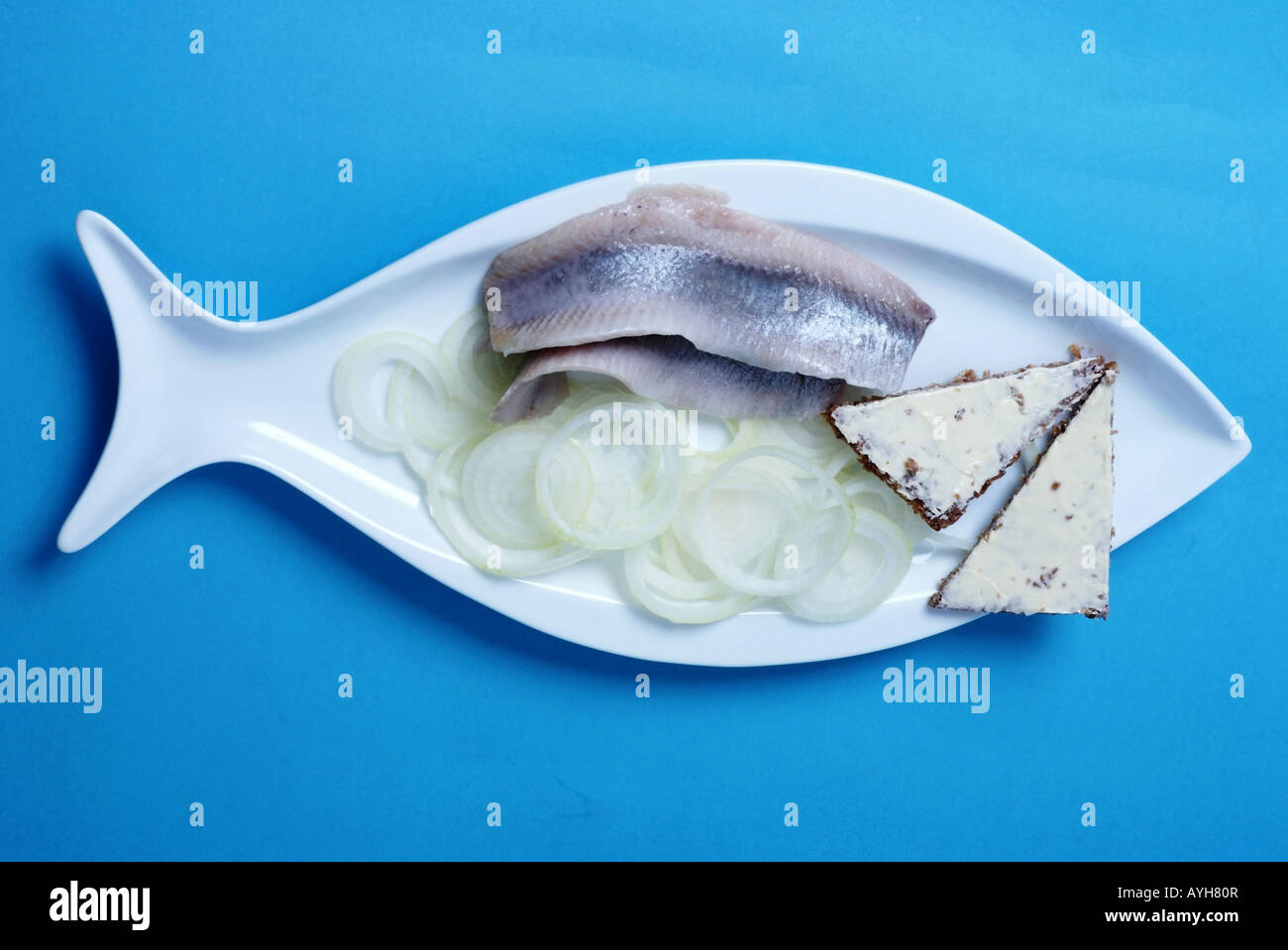 Matjes pesce su una piastra bianca con cipolle e allevati | Matjes mit Brot und Zwiebeln Foto Stock