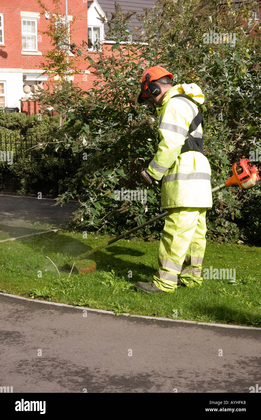 Workman strimming erba sconfinano Cardiff Regno Unito Foto Stock