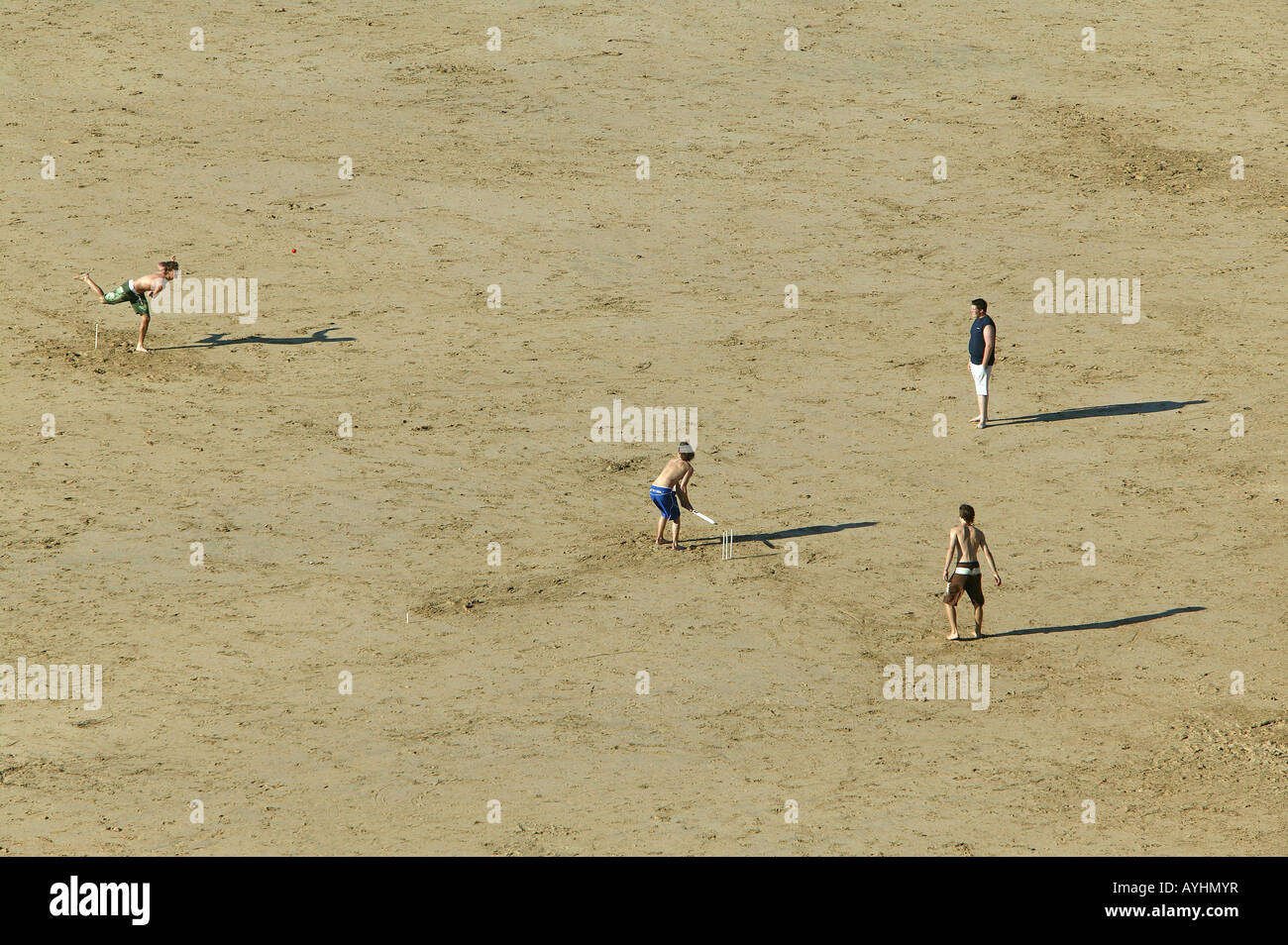 Giovani uomini giocando una partita di cricket in spiaggia Foto Stock