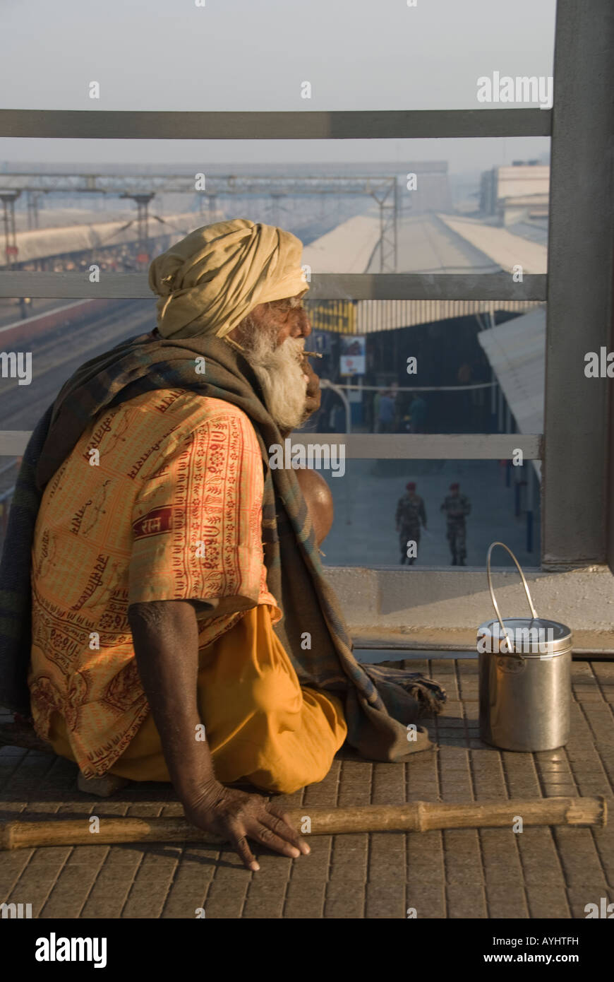 Il vecchio uomo di fumare e di accattonaggio in una stazione ferroviaria in Agra, India Foto Stock