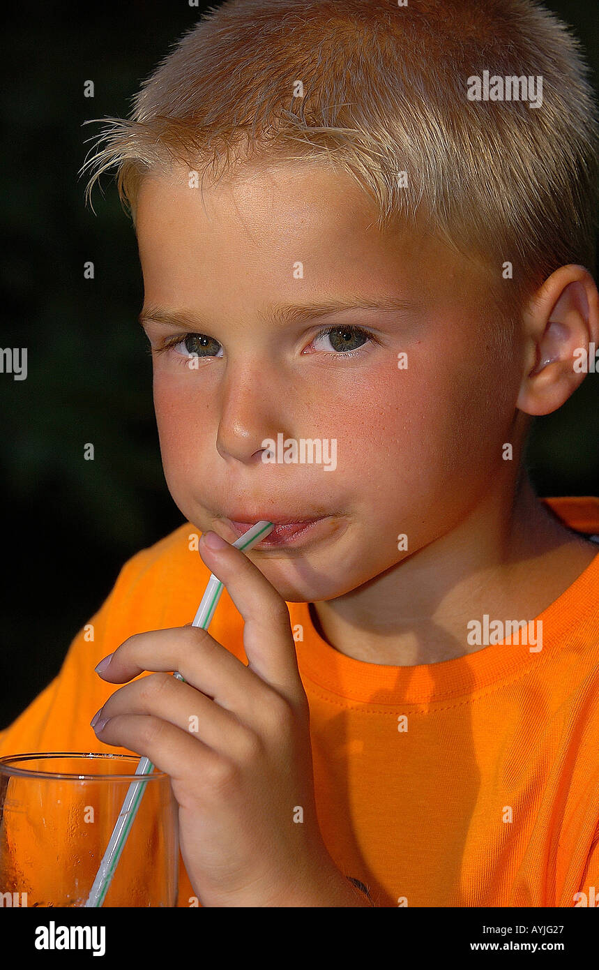 Kleiner Junge blondr trinkt Mit einem Trinkhalm aus einem Glas Foto Stock