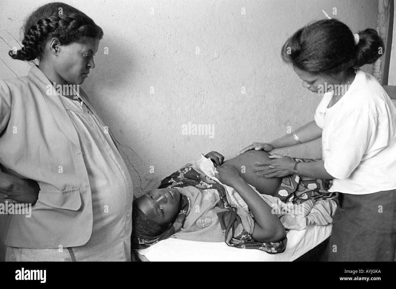 B/N di un'ostetrica e della sua assistente in gravidanza che esamina una donna incinta in una clinica di salute rurale. Dessie, Etiopia, Africa Foto Stock