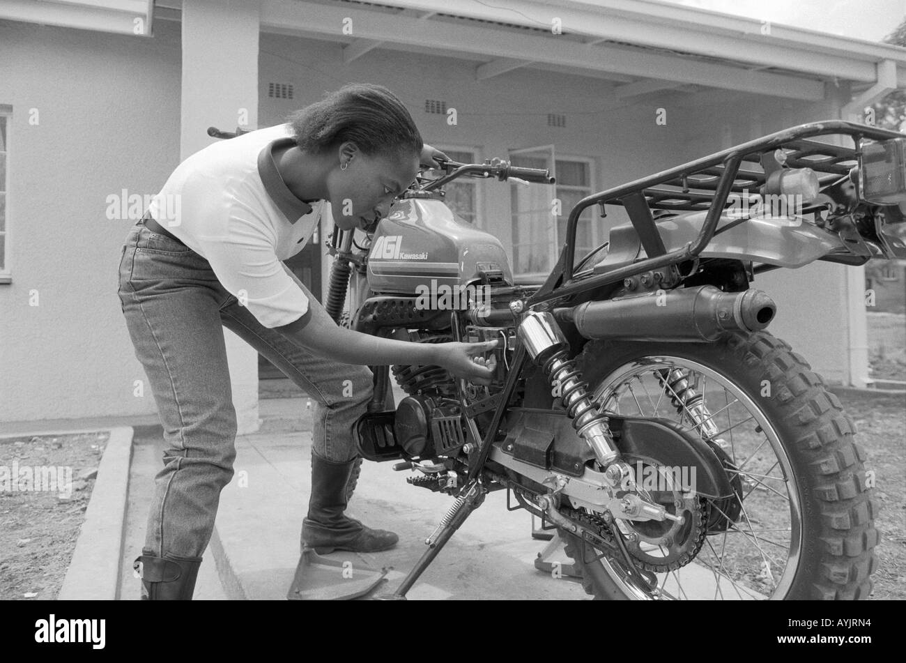 B/W di un operatore sanitario che pulisce la sua moto sul programma Riders for Health, portando l'assistenza sanitaria nelle aree rurali remote del Lesotho, Africa del Sud Foto Stock