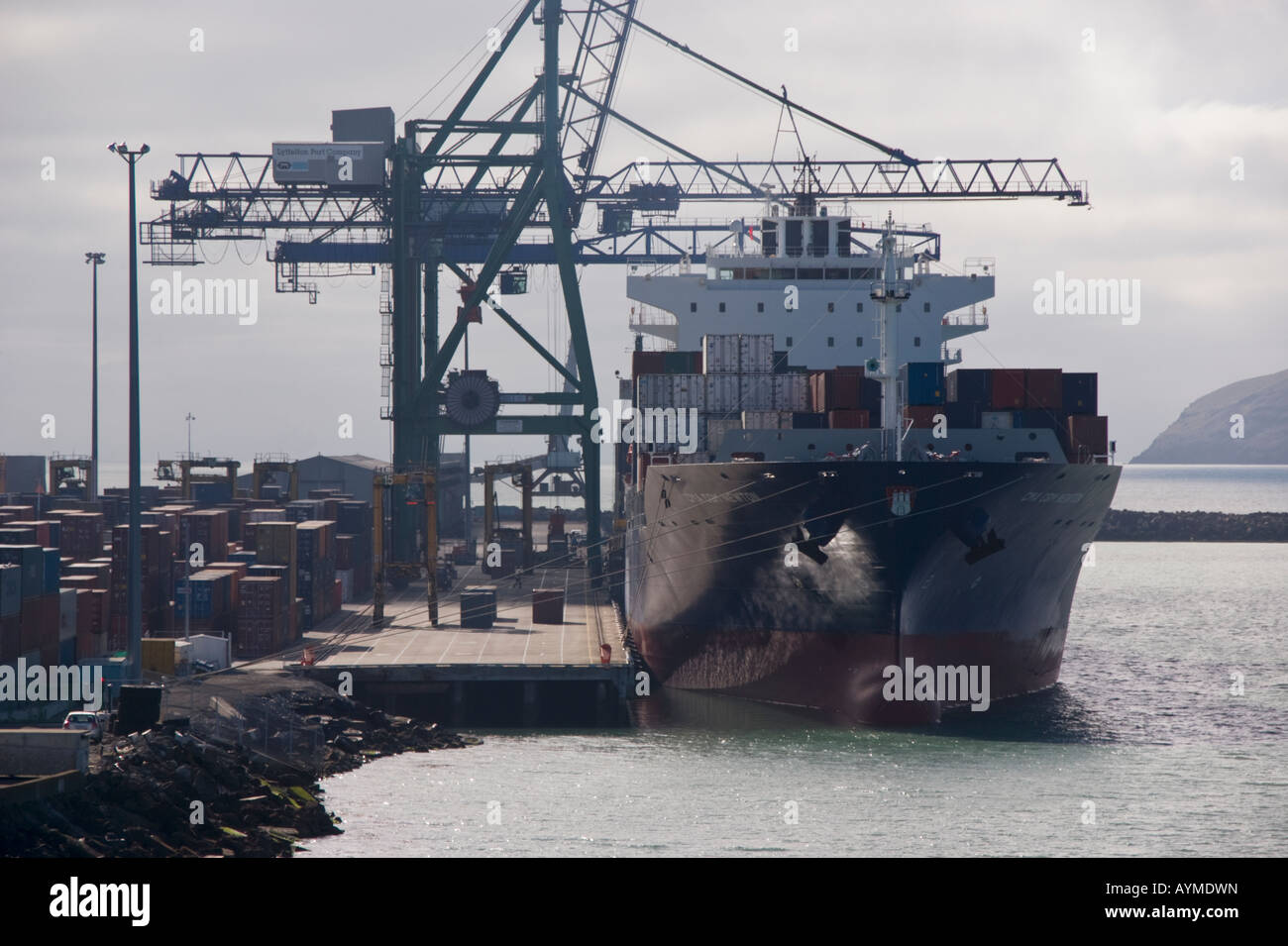 Una nave portacontainer a fianco del dock con gru shore a lavoro, Lyttelton, Nuova Zelanda Foto Stock