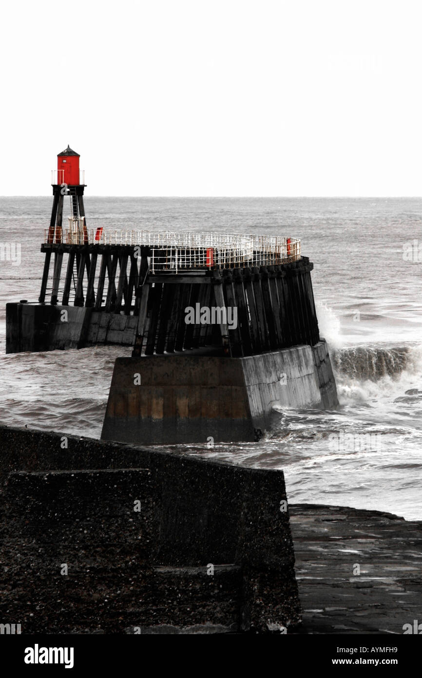 Pier e difese di mare con onde moderate Whitby North Yorkshire monocromatico rosso plus Foto Stock