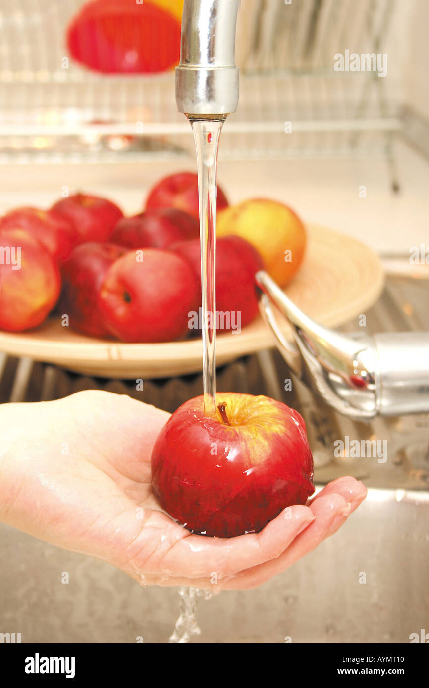 Einen Apfel unter laufendem Wasser abwaschen Foto Stock