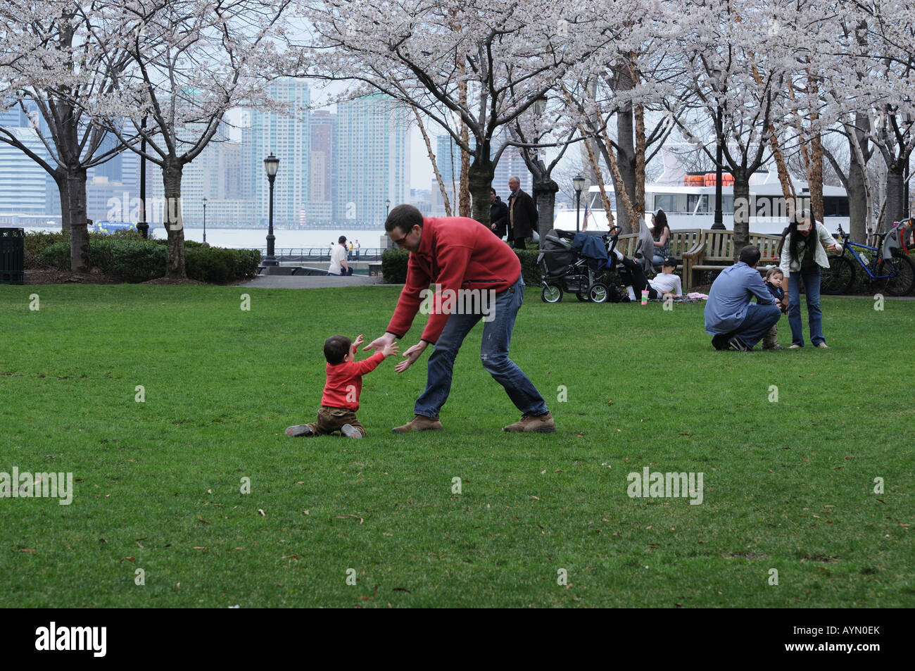In una bella giornata di primavera in Battery Park City, un padre aiuta il suo figlio che è caduto come si impara a camminare. Foto Stock
