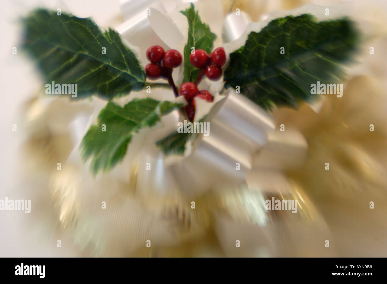 Fantasia di prua di Natale con holly foglie e bacche su un elegante regalo di Natale con il bianco di raso Foto Stock